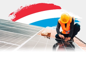 An installer mounts a solar panel on a tiled roof, with the Luxembourg flag in the background.